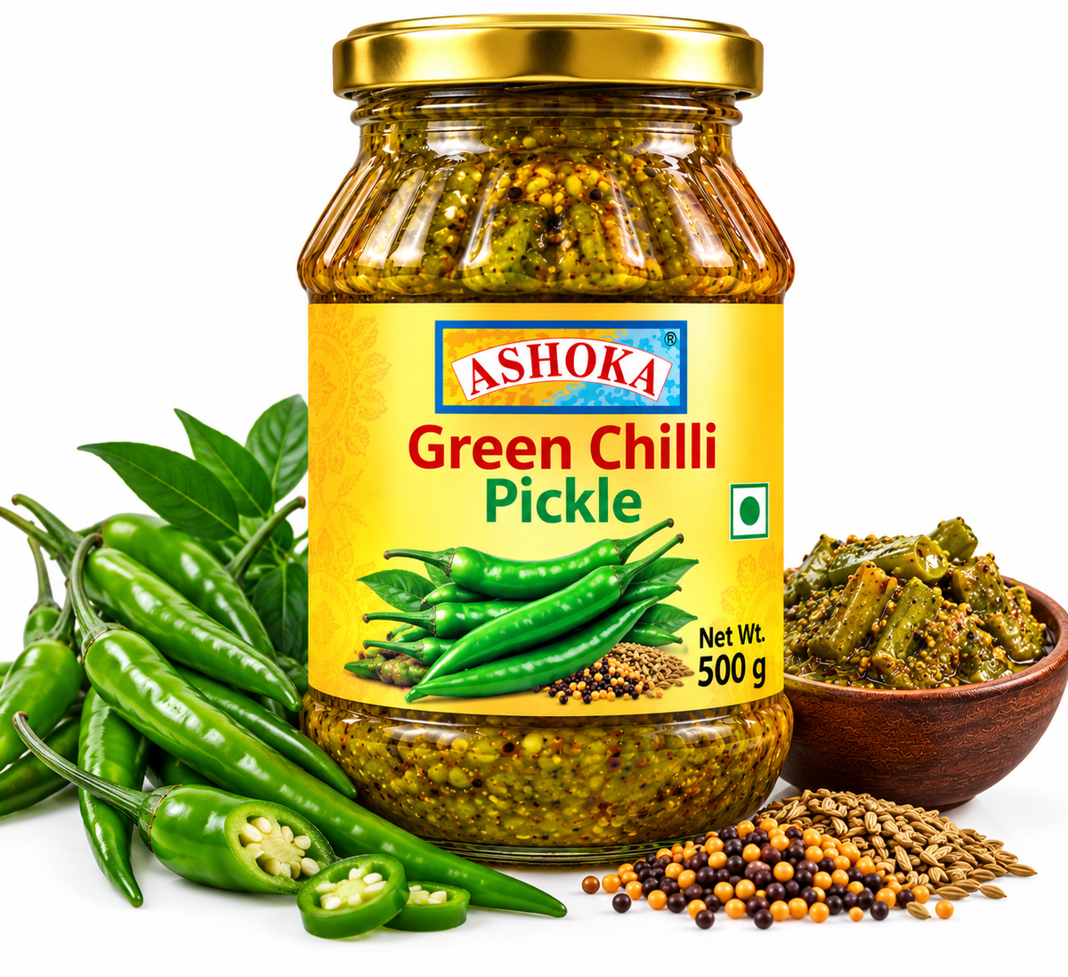 Ashoka Green Chilli Pickle 500g featuring a glass jar with a gold lid and bright yellow label, filled with traditional green chilli pickle, alongside fresh green chillies, sliced chillies, green leaves, mustard seeds, and aromatic Indian spices.
