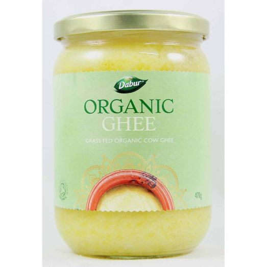 Glass jar of Dabur Organic Ghee with a light green label and gold lid, labeled “Organic Ghee – Grass Fed Organic Cow Ghee,” containing golden clarified butter, 470g size.