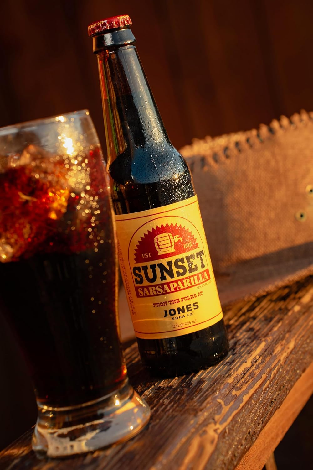 A single 355ml glass bottle of Jones Soda x Fallout Sunset Sarsaparilla. The clear bottle contains dark brown soda and features a Fallout-themed label with retro Americana styling inspired by the video game series.