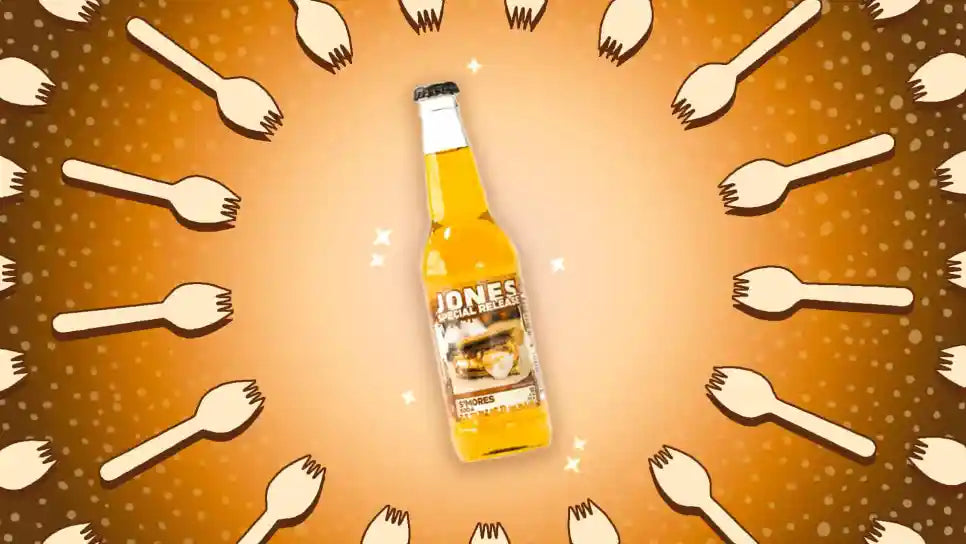 A 355ml glass bottle of Jones Soda Special Release S’mores Soda featuring a dessert-themed label and light brown soda visible through clear glass.