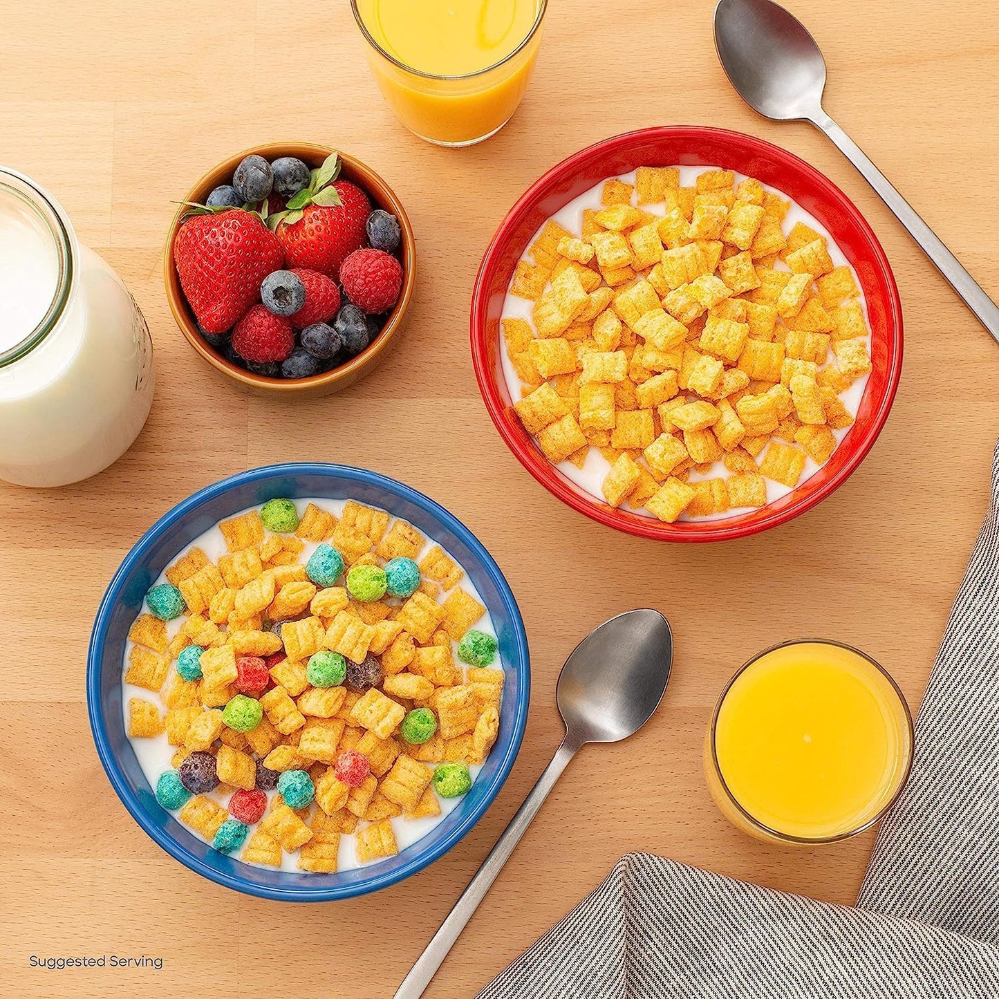 Top view of Cap'n Crunch cereal served with milk in colourful breakfast bowls, accompanied by fresh berries, orange juice and milk for a delicious morning meal.