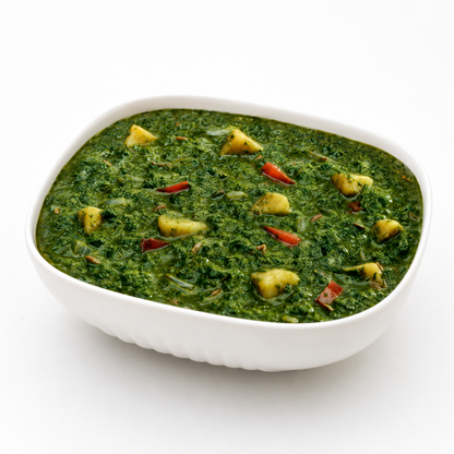 Ashoka Saag Aloo served in a white bowl with spinach and potato curry on a clean white background.