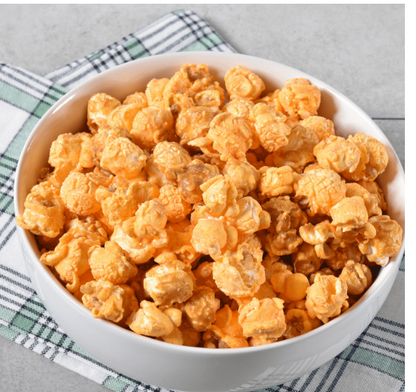 Shaker jar of Kernel Season’s Bacon Cheddar Seasoning with a sprinkling on freshly popped popcorn.