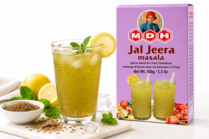 MDH Jal Jeera Masala 100g spice blend packet displayed beside a refreshing glass of yellow-green jal jeera drink served with ice, fresh lemon slices, mint leaves, and cumin seeds. The scene highlights the traditional Indian spiced beverage, with the purple MDH packaging clearly showing the product name and net weight. Ideal for preparing a tangy, refreshing jal jeera drink at home.