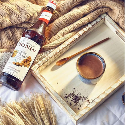 700 ml bottle of Monin Salted Caramel Syrup, rich amber liquid with buttery caramel and subtle sea salt flavor, vegan-friendly and allergen-free, ideal for coffee, cocktails, and desserts.