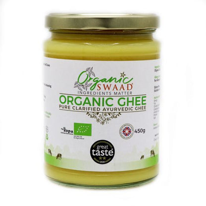 Front-facing image of Organic Swaad Organic Ghee 450g in a clear glass jar with gold lid, displaying organic certification logos and pure clarified butter made in the UK from grass-fed milk.