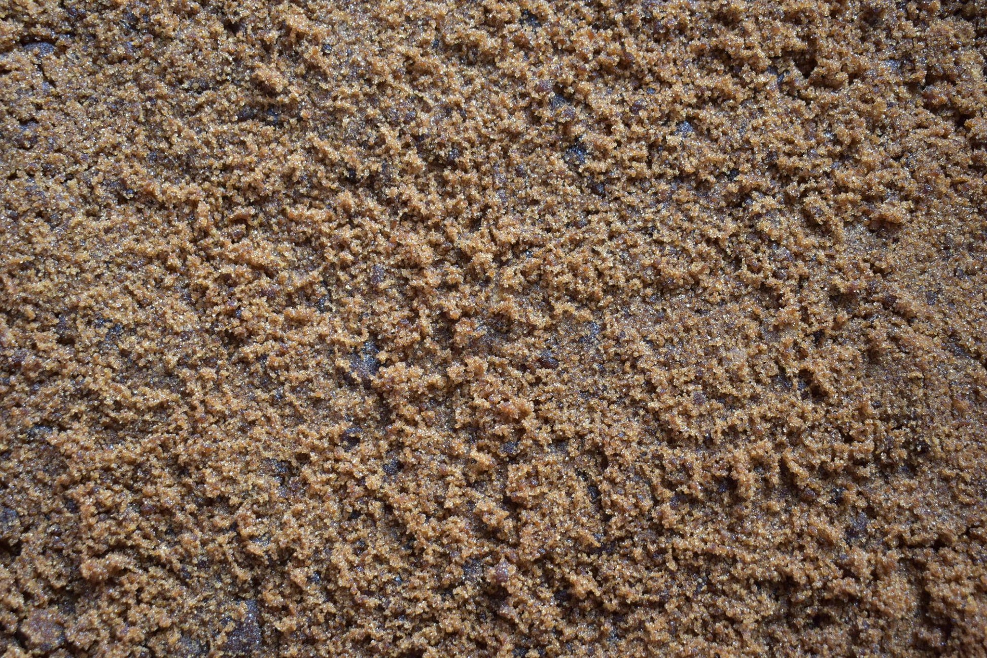 Close-up of organic jaggery powder showing fine golden-brown unrefined cane sugar texture used for Indian sweets and tea.