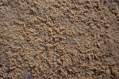 Close-up of organic jaggery powder showing fine golden-brown unrefined cane sugar texture used for Indian sweets and tea.