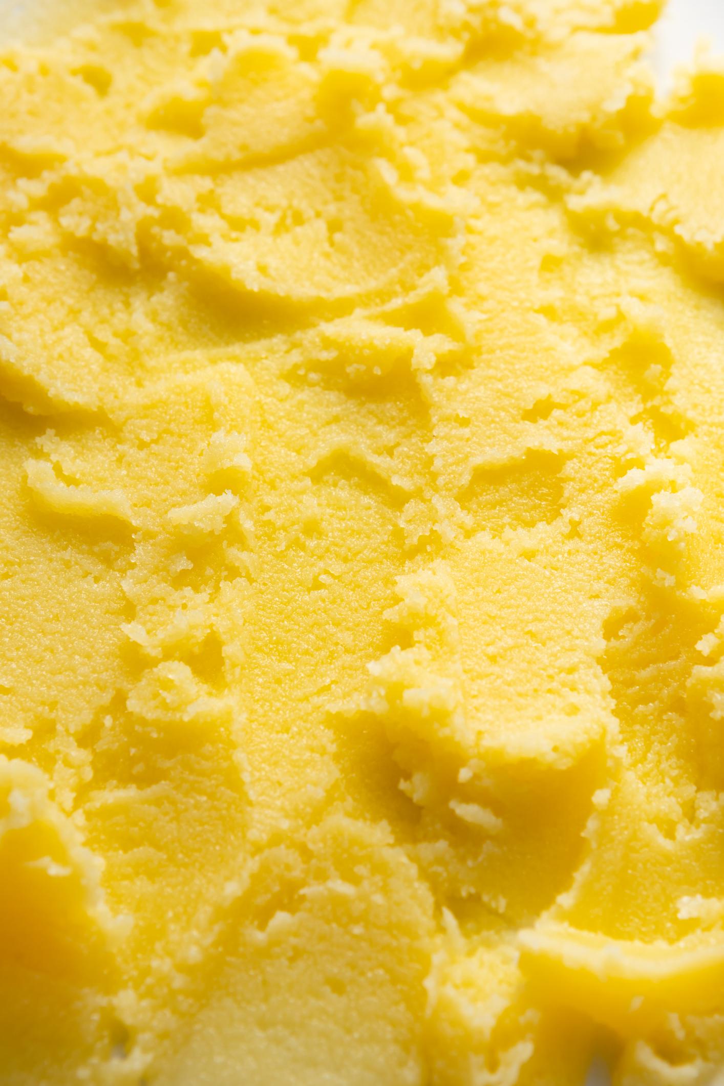 Close-up of golden organic ghee showing smooth, creamy clarified butter texture with soft ridges and rich yellow colour.