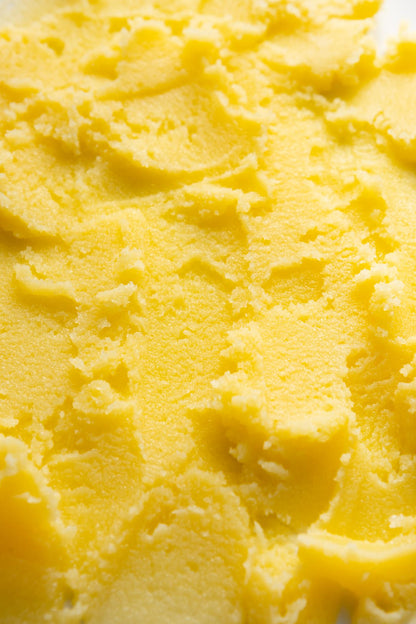 Close-up of golden organic ghee showing smooth, creamy clarified butter texture with soft ridges and rich yellow colour.
