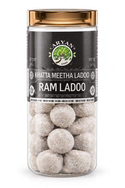 Aryan Khatta Meetha Ladoo 160g in a clear plastic jar with a gold-toned lid, dark charcoal label, green tree logo, and pale, sugar-dusted round ladoos visible through the transparent packaging against a clean white background.