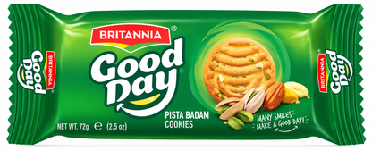 Golden Britannia Good Day-style pista badam cookies with pistachio and almond pieces arranged on a plate beside a cup of tea on a wooden board.