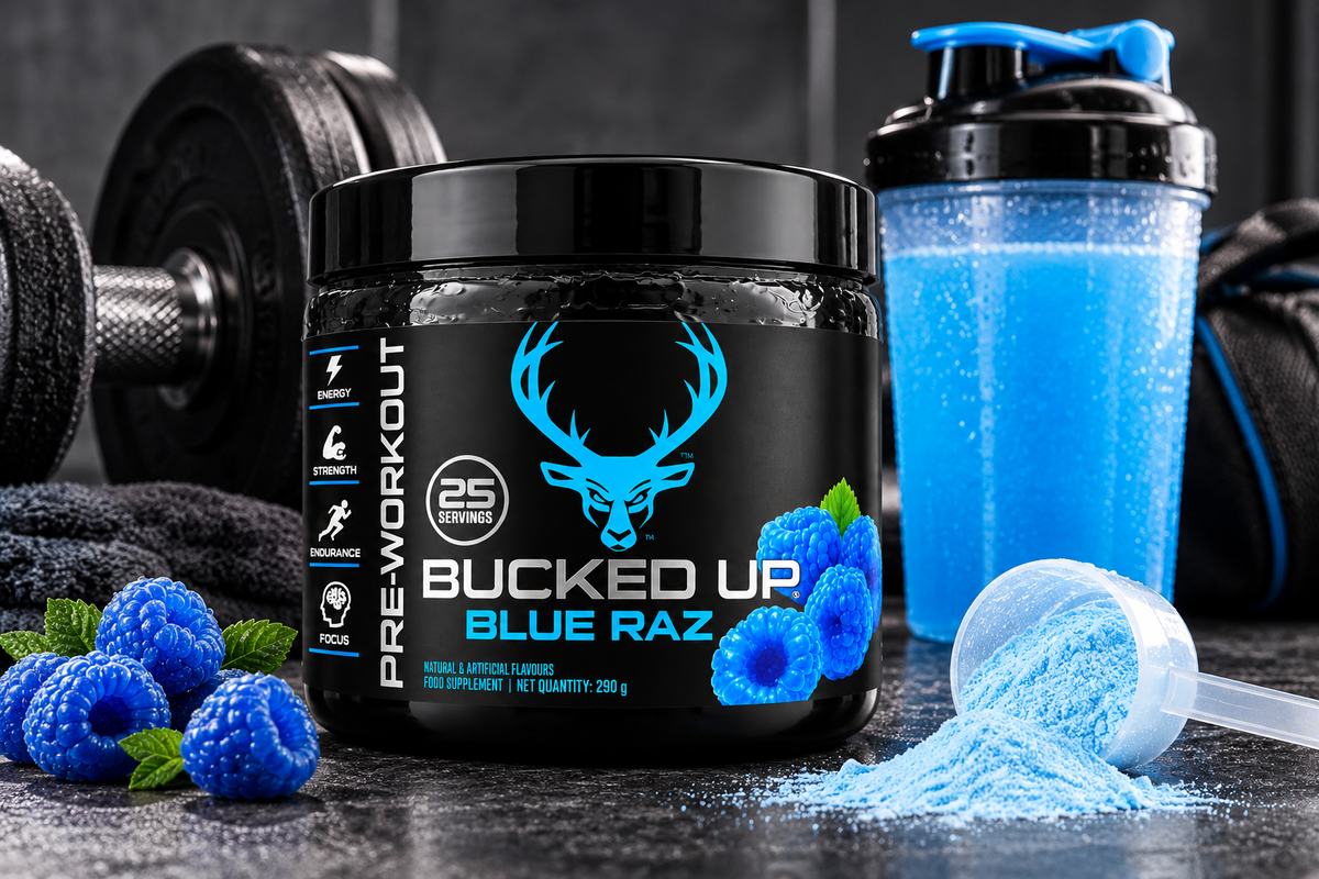 Bucked Up Blue Raz Pre-Workout Powder 290g displayed in a gym setting with blue shaker bottle, dumbbells, blue raspberries and pre-workout powder scoop.