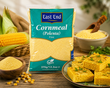 A bag of East End Cornmeal (Polenta) Fine stands on a rustic wooden table surrounded by corn, bowls of yellow cornmeal, and cornbread slices garnished with parsley.