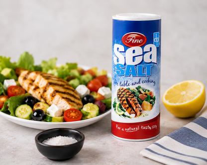 Fine Sea Salt 500g presented in a stylish kitchen serving display with grilled chicken salad, lemon and sea salt crystals, highlighting its natural flavour and versatility for everyday cooking and table seasoning.