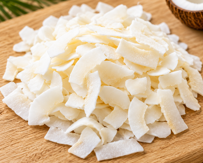Close-up image of premium coconut chips on a wooden board, highlighting their natural texture, freshness and versatility for cooking, baking and healthy snacks.