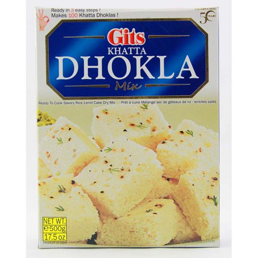 Gits Khatta Dhokla Mix 500g box packaging showing soft, light steamed dhokla cubes garnished with mustard seeds, ready-to-cook Gujarati savory mix.