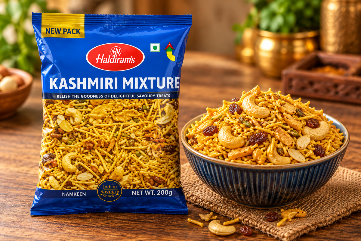 Haldiram Kashmiri Mixture 200g packet displayed beside a bowl of savoury snack mix with golden sev, cashews and raisins on a rustic wooden table.