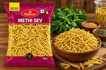 Haldiram Methi Sev 200g packet displayed beside a bowl of golden methi sev on a rustic wooden table with fresh herbs and spices.
