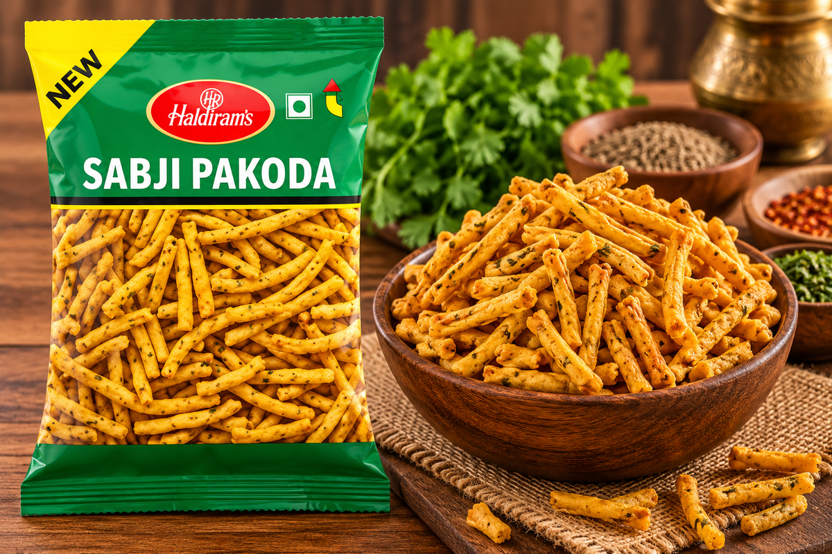 Haldiram Sabji Pakora 200g packet displayed beside a wooden bowl of golden, crispy savoury snacks in a rustic food setting.