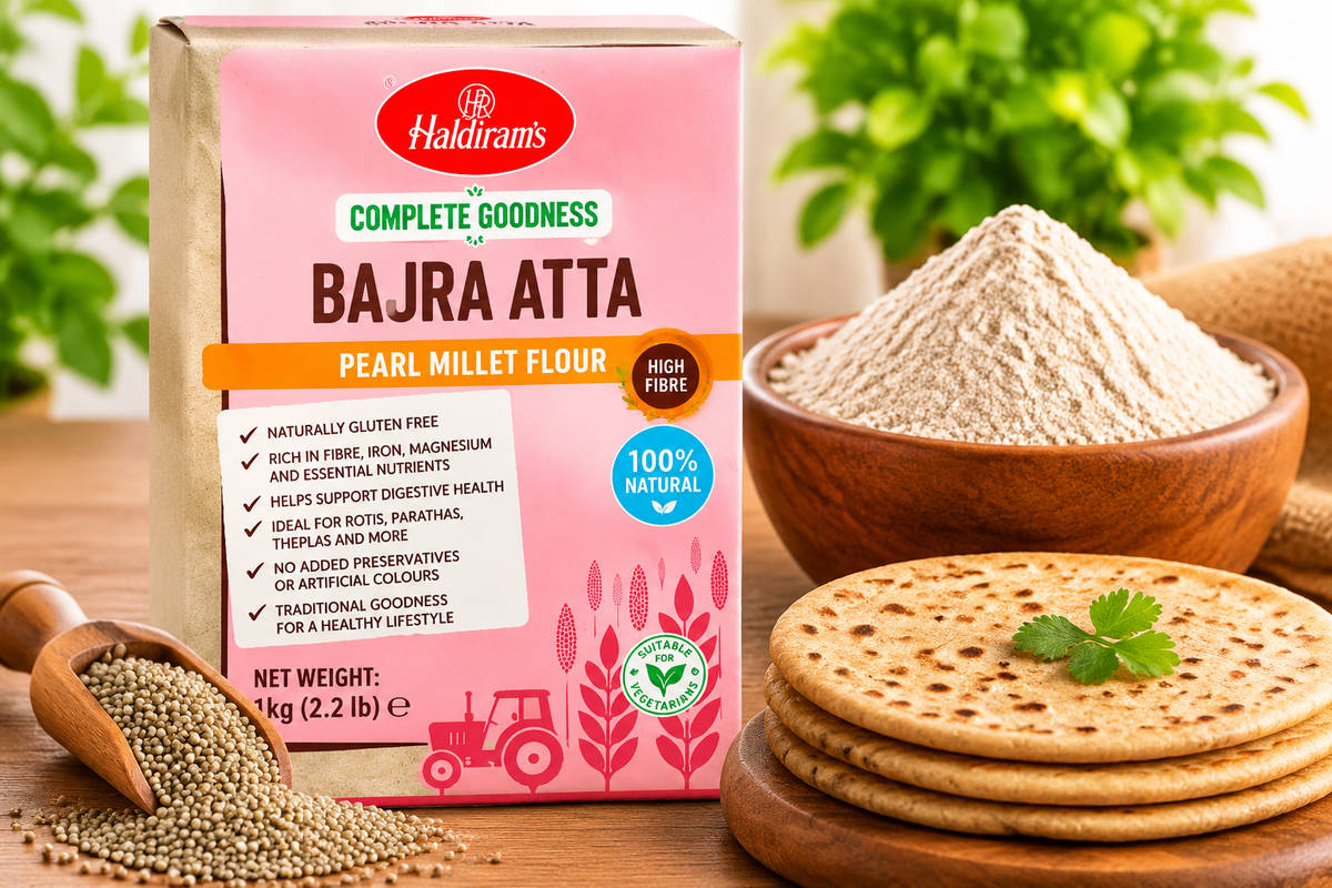 Haldiram’s Bajra Atta Pearl Millet Flour pack displayed with a bowl of bajra flour, pearl millet grains and freshly cooked rotis on a wooden table.