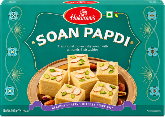 Haldiram’s Soan Papdi 500g front packaging featuring traditional flaky Indian sweet with almonds and pistachios, teal green decorative box design, Haldiram’s branding, vegetarian symbol and serving suggestion