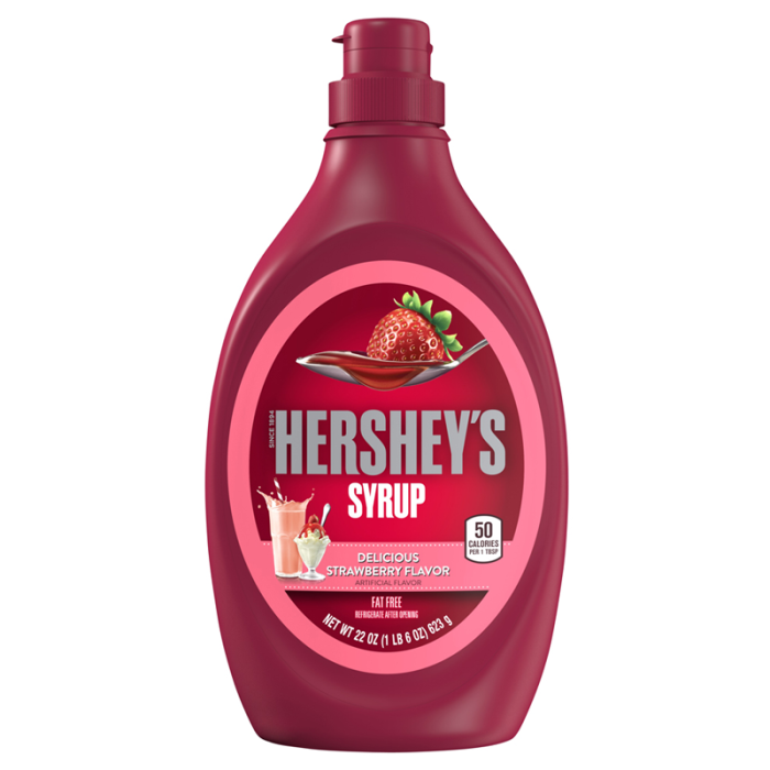 Hand squeezing Hershey's Strawberry Syrup over a bowl of yogurt with fresh strawberries for a sweet treat.