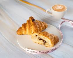 Like Home chocolate croissant cut open showing creamy chocolate filling on white plate with coffee