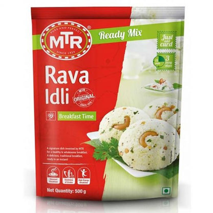 Front view of MTR Rava Idli Ready Mix 500g packet, red and green packaging, showing three steamed rava idlis garnished with cashews on a white plate, labeled “Ready Mix” and “Breakfast Time.”