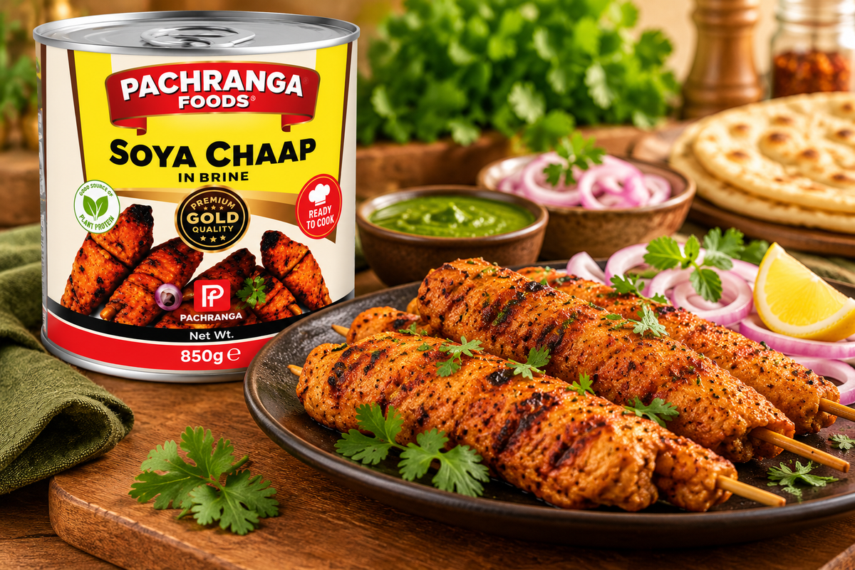 Pachranga Foods Soya Chaap in Brine 850g tin with grilled soya chaap skewers, fresh coriander, onion rings, green chutney and lemon wedges on a wooden table.