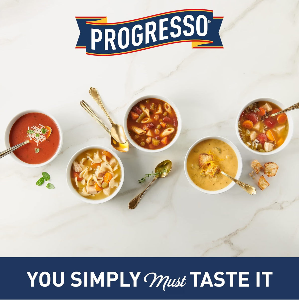 Progresso soup brand promotional image featuring the Progresso logo above five bowls of assorted soups, including tomato soup, pasta soup, chicken noodle soup and creamy soup varieties, with the slogan “You Simply Must Taste It” on a navy blue banner.