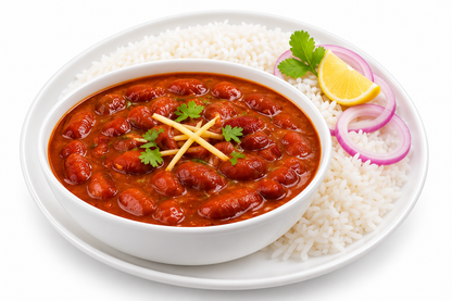 Indian rajma raseela curry garnished with ginger and coriander, served with basmati rice, sliced red onion and lemon on a white plate against a white background