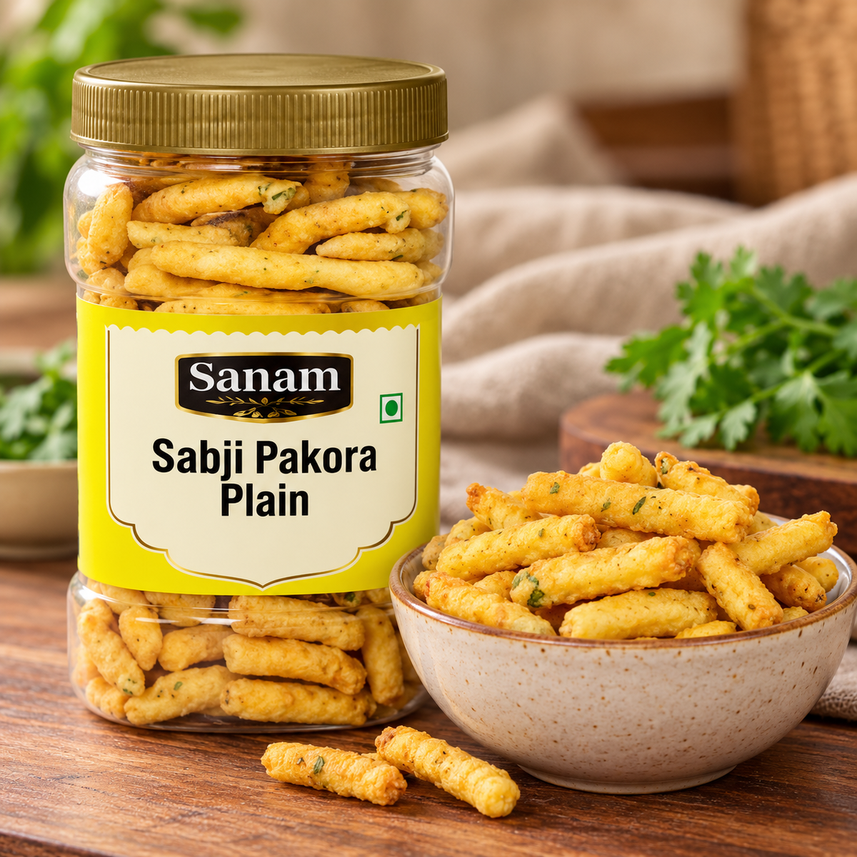 Sanam Plain Sabji Pakora 400g jar displayed beside a bowl of golden savoury pakora snacks on a wooden table, showcasing the crunchy Indian snack in a warm, rustic food setting for tea-time and everyday snacking.