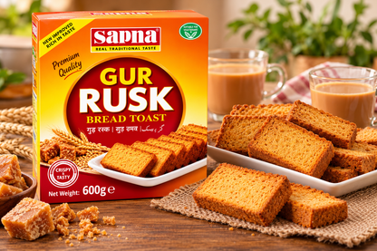 Sapna Gur Rusk 600g with Crispy Golden Rusks, Jaggery Pieces, Wheat Stalks and Cups of Tea on a Wooden Table