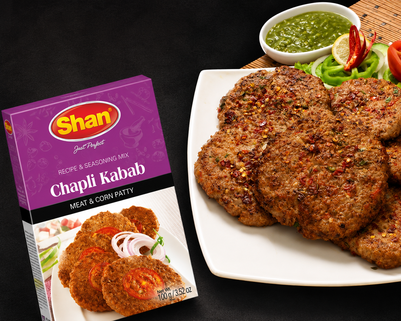 Shan Chapli Kabab seasoning mix box shown next to a white plate of cooked meat and corn patties with green chutney on a dark background.